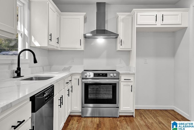 kitchen with appliances with stainless steel finishes, wall chimney exhaust hood, white cabinets, and sink