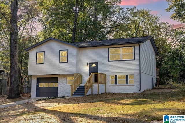 split foyer home featuring a lawn and a garage