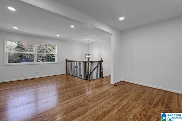 unfurnished room with hardwood / wood-style flooring and an inviting chandelier