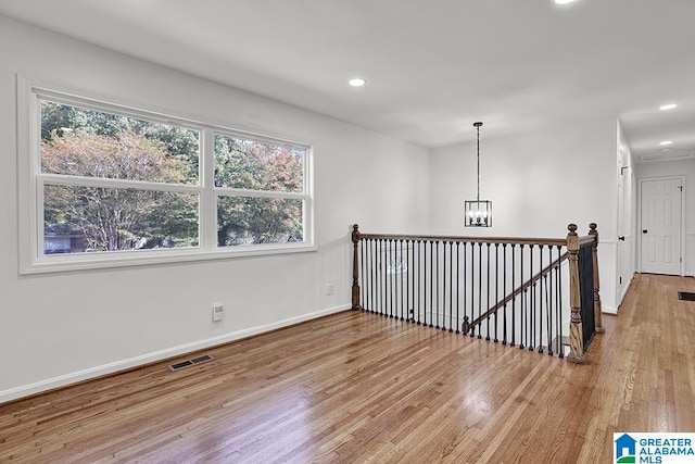 empty room with an inviting chandelier and wood-type flooring