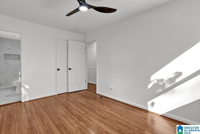 unfurnished bedroom featuring ensuite bath, light hardwood / wood-style floors, and ceiling fan