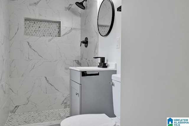 bathroom with toilet, vanity, and tiled shower