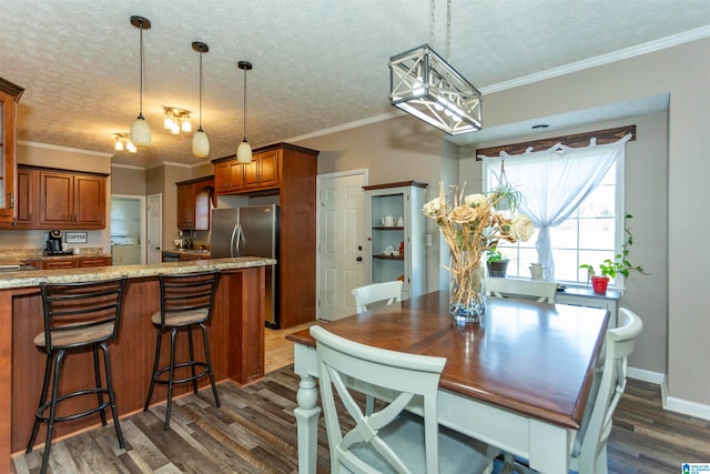 dining room with dark wood-type flooring, ornamental molding, and a textured ceiling