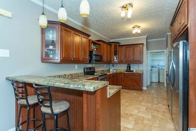 kitchen with a breakfast bar area, kitchen peninsula, appliances with stainless steel finishes, light stone counters, and washing machine and dryer