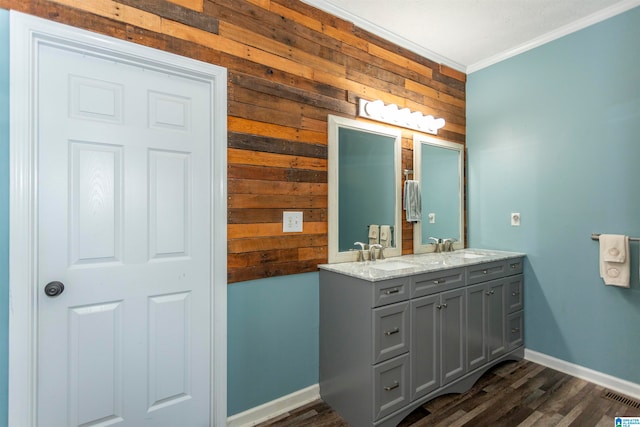 bathroom featuring vanity, ornamental molding, hardwood / wood-style flooring, and wooden walls