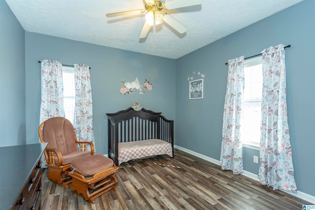 bedroom with a textured ceiling, multiple windows, dark hardwood / wood-style floors, and ceiling fan