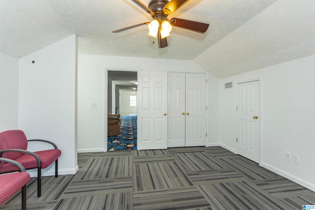 carpeted bedroom with lofted ceiling, a textured ceiling, a closet, and ceiling fan