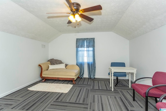 living area with lofted ceiling, dark colored carpet, a textured ceiling, and ceiling fan