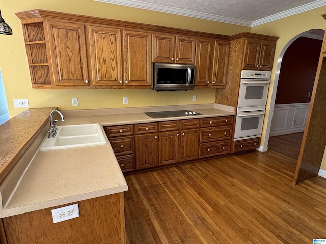 kitchen featuring double oven, black electric cooktop, sink, ornamental molding, and dark hardwood / wood-style floors