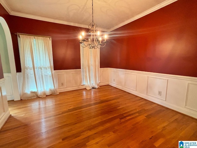 unfurnished dining area featuring a chandelier, hardwood / wood-style floors, and crown molding