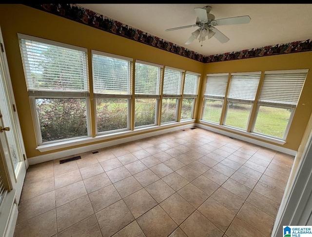 unfurnished sunroom featuring ceiling fan and a wealth of natural light