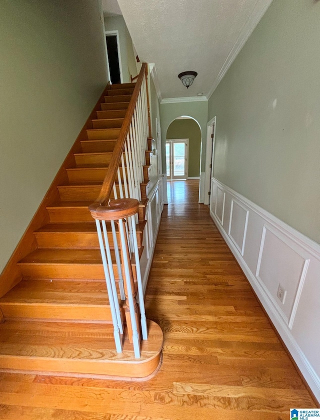 stairway featuring hardwood / wood-style flooring, crown molding, and a textured ceiling