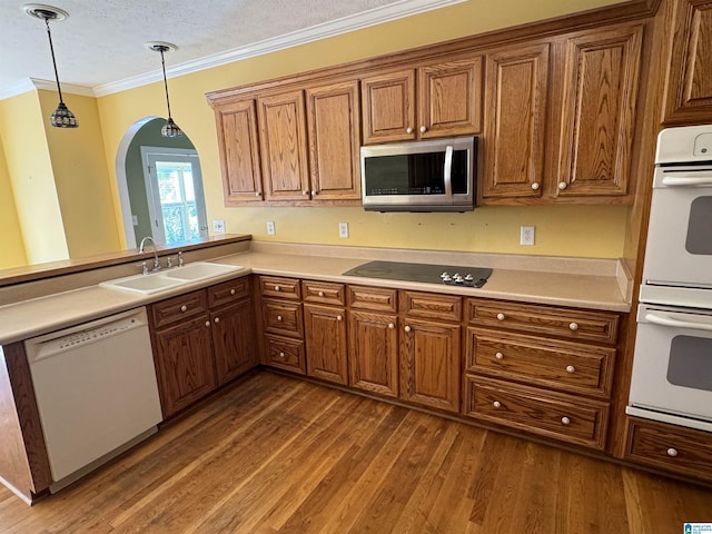 kitchen with white appliances, a textured ceiling, hanging light fixtures, sink, and dark hardwood / wood-style floors