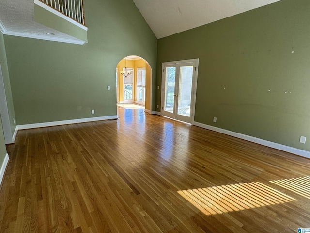 unfurnished living room with high vaulted ceiling, hardwood / wood-style floors, and a chandelier