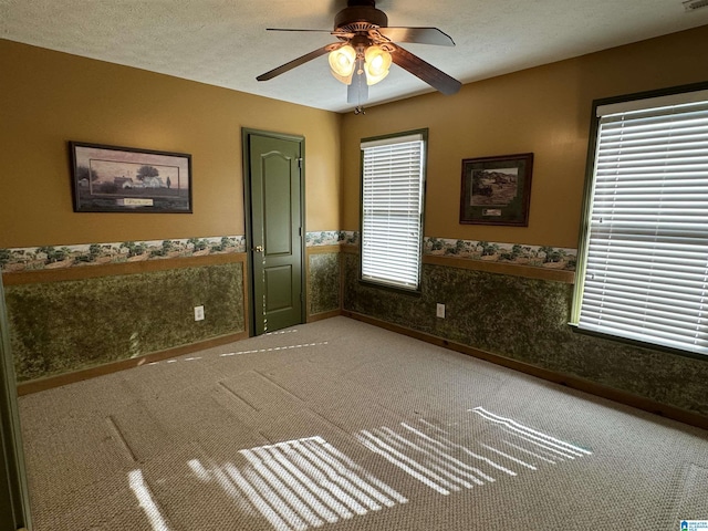 carpeted spare room featuring a textured ceiling and ceiling fan