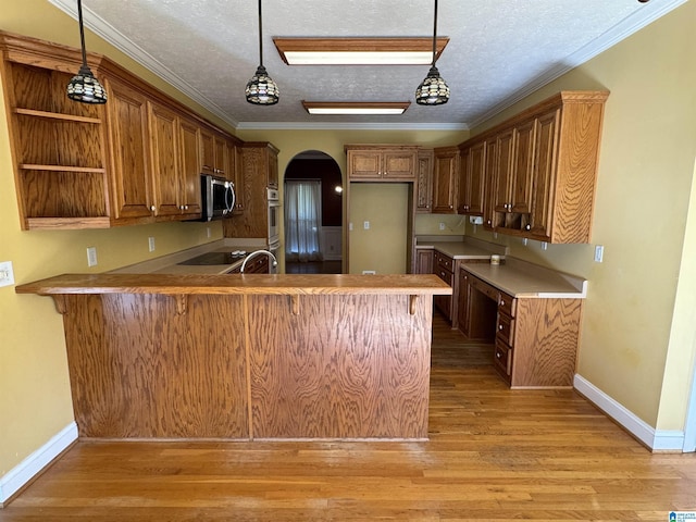 kitchen with kitchen peninsula, crown molding, light hardwood / wood-style flooring, appliances with stainless steel finishes, and a textured ceiling