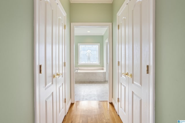 hallway featuring crown molding and light hardwood / wood-style flooring