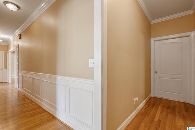 corridor with ornamental molding and light hardwood / wood-style flooring