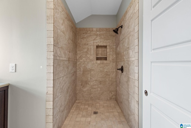 bathroom with vanity, lofted ceiling, and tiled shower