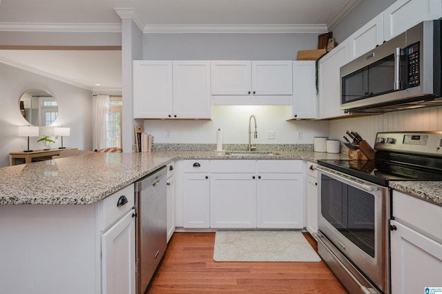 kitchen featuring appliances with stainless steel finishes, sink, kitchen peninsula, light hardwood / wood-style floors, and white cabinets