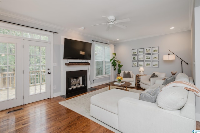 living room with ceiling fan, crown molding, and wood-type flooring