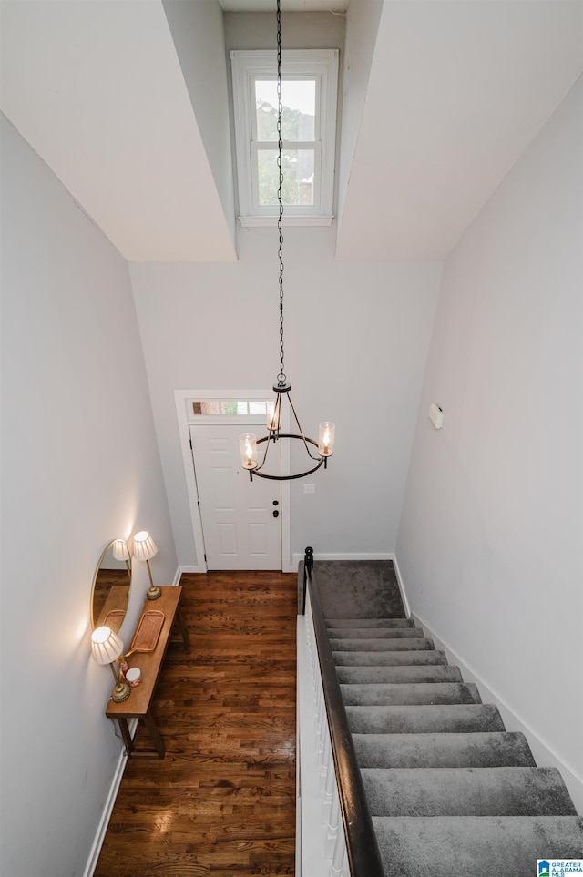 stairway featuring lofted ceiling, a chandelier, and wood-type flooring