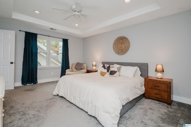 carpeted bedroom featuring ceiling fan and a raised ceiling