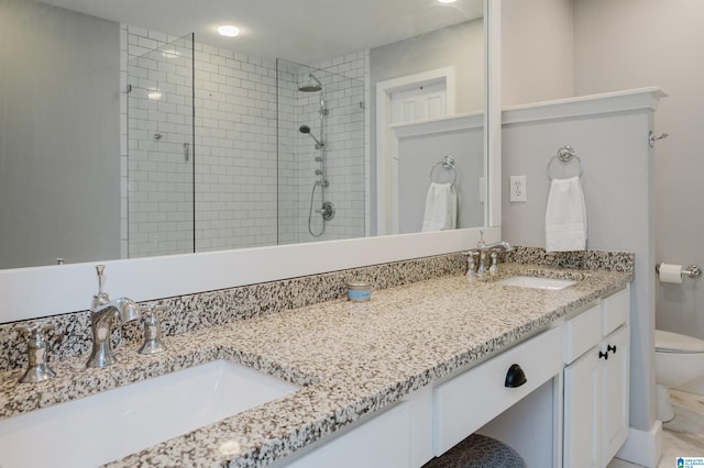 bathroom with vanity, toilet, and tiled shower