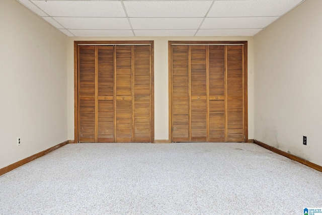 unfurnished bedroom with multiple closets, a paneled ceiling, and carpet flooring