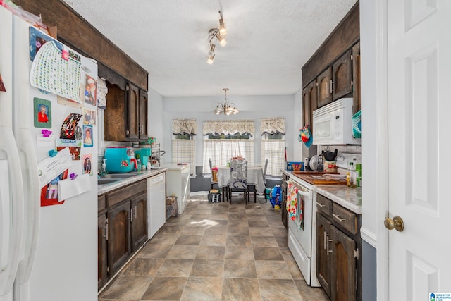 kitchen featuring dark brown cabinetry, hanging light fixtures, and white appliances