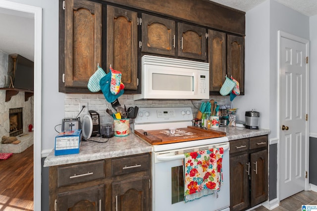 kitchen featuring white appliances, light hardwood / wood-style floors, a textured ceiling, and dark brown cabinets