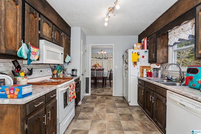 kitchen with sink, dark brown cabinetry, a notable chandelier, a textured ceiling, and white appliances