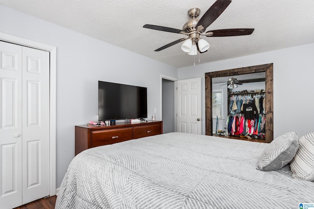 bedroom with dark hardwood / wood-style floors, two closets, a textured ceiling, and ceiling fan