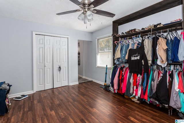 walk in closet with dark wood-type flooring and ceiling fan