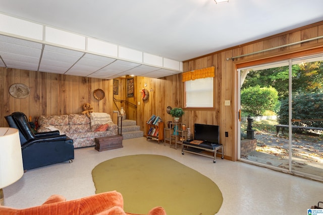 living room with a drop ceiling and wooden walls