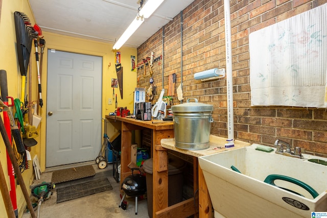 interior space featuring brick wall, sink, and concrete flooring