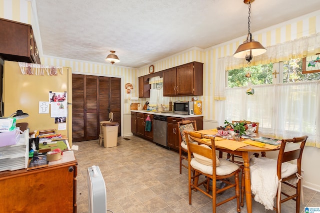 kitchen with decorative light fixtures, stainless steel appliances, and a textured ceiling