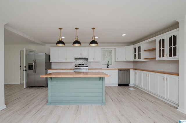 kitchen with a kitchen island, white cabinetry, appliances with stainless steel finishes, pendant lighting, and light hardwood / wood-style flooring