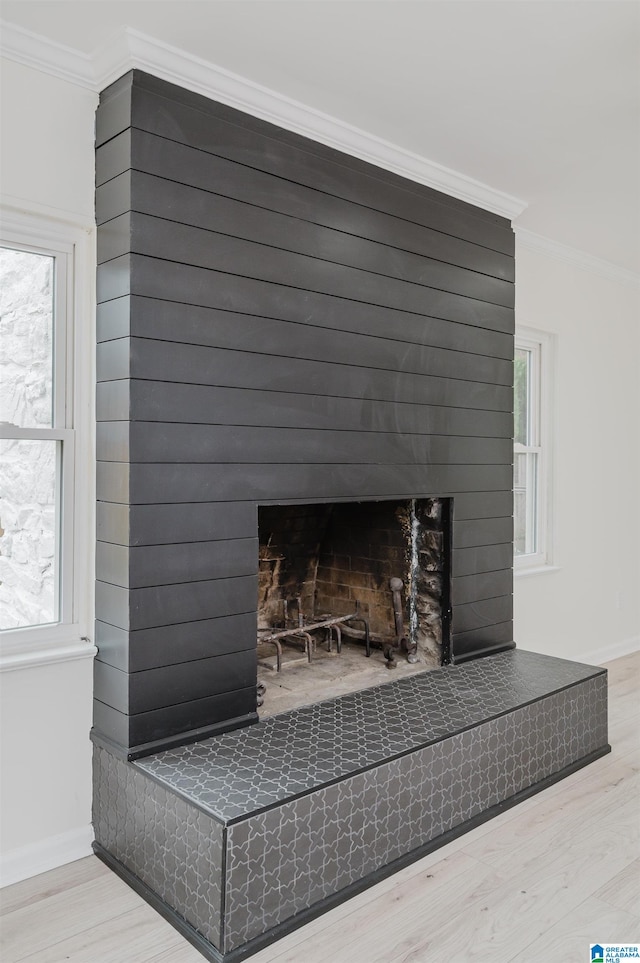 interior details with a tiled fireplace, wood-type flooring, and crown molding