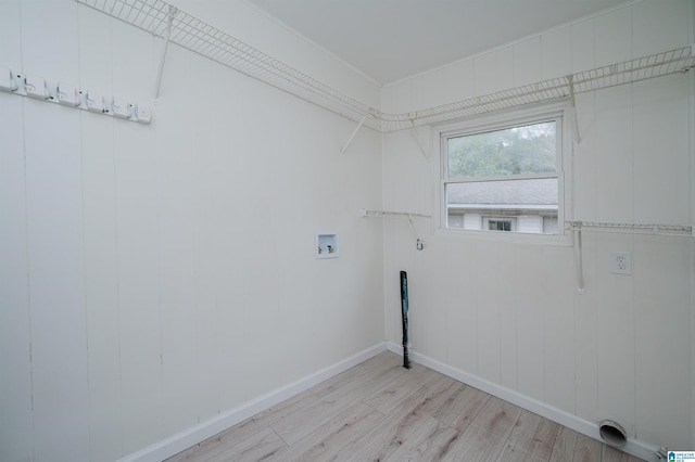 clothes washing area with light hardwood / wood-style floors, wooden walls, and hookup for a washing machine