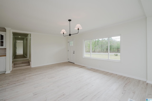 empty room with light wood-type flooring, an inviting chandelier, and ornamental molding