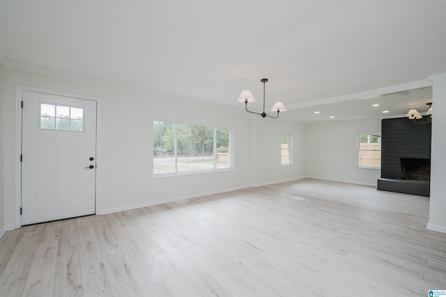 unfurnished living room featuring a wealth of natural light, a chandelier, and light hardwood / wood-style floors