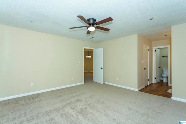 empty room with a textured ceiling, ceiling fan with notable chandelier, and carpet