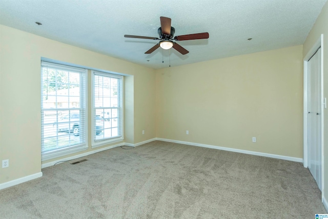 carpeted spare room featuring a textured ceiling and ceiling fan