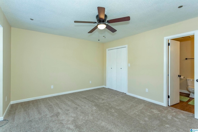 unfurnished bedroom featuring ensuite bathroom, a textured ceiling, a closet, ceiling fan, and light colored carpet