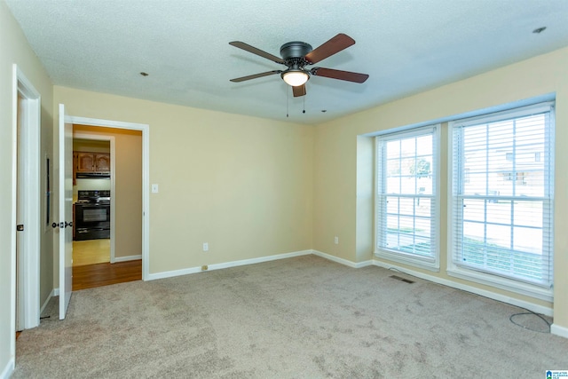 carpeted spare room featuring a textured ceiling and ceiling fan