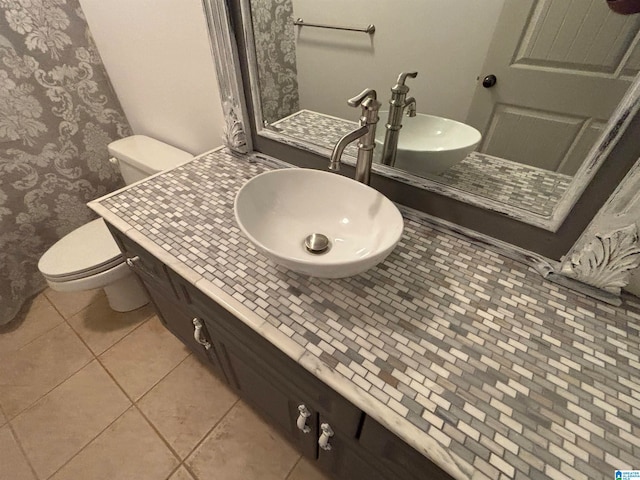 bathroom with toilet, vanity, and tile patterned flooring