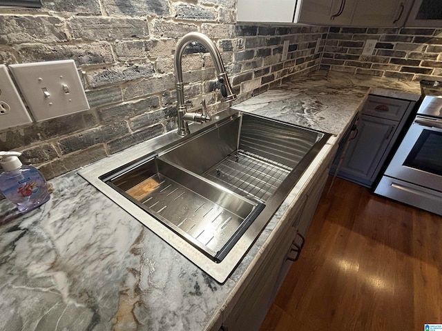 kitchen featuring dark hardwood / wood-style floors, sink, backsplash, and stainless steel range oven