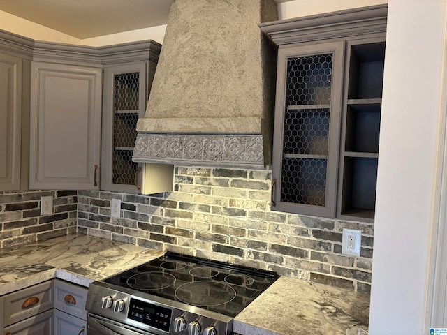 kitchen with premium range hood, stainless steel range with electric stovetop, light stone counters, and gray cabinetry