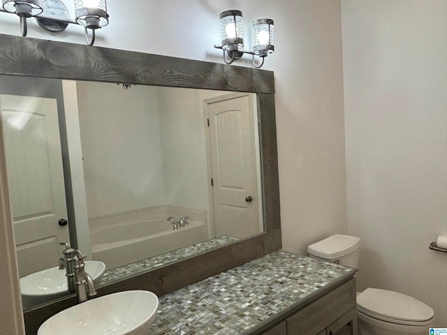 bathroom with vanity, a bathing tub, and toilet